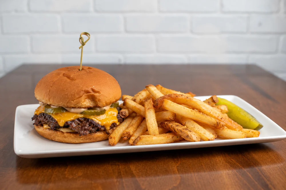 Smash burger with cheddar, pickles, house sauce, and fries