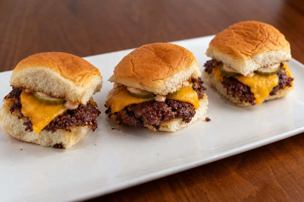 Three smash sliders with cheddar, pickles, and house sauce